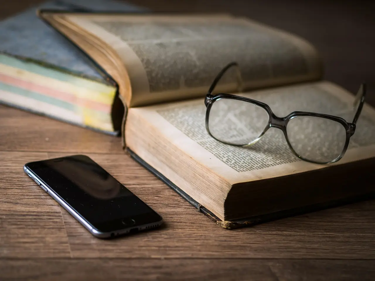Okulary do czytania na książce obok smartfona